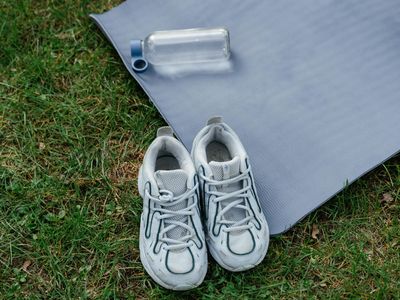 Sport shoes and a water bottle on a mat.
